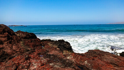 Ocean horizon with foamy waves crashing on coastal rocks