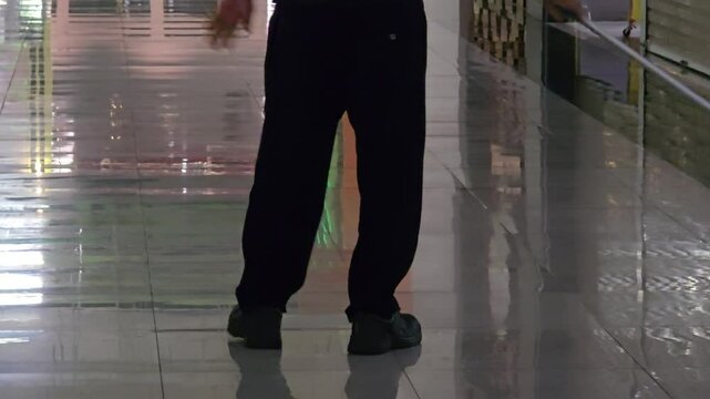 Rear view of mall cleaner mopping the floor, concept of public space cleanliness