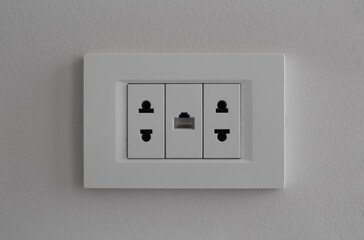 Horizontal defocused photo. Front view. White electrical outlet and LAN port for internet on beige-gray hotel wall. Concept of charging device, connect, network, ethernet, power, tech. Selective focus
