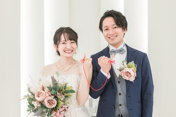 結婚式場で赤い糸で結ばれる新郎新婦（ブライダル・ウェディング）
