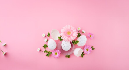 Fototapeta premium Pink flowers and white eggs are arranged with green leaves on a soft pink backdrop, creating a delicate spring or Easter themed composition.