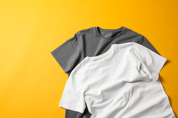Blank t-shirts on yellow background, flat lay. Mockup for design