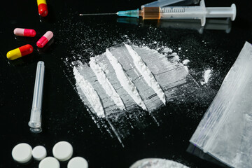 Drug addiction. Powder, pills and syringe on black table, closeup