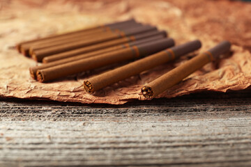 Dried tobacco leaf and cigarettes on wooden table, closeup