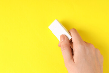 Woman using eraser on yellow background, closeup. Space for text