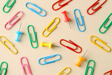 Paper clips and pins on beige background, flat lay