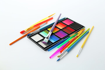 Naklejka premium Bright face paint palette and brushes isolated on white