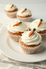 Tasty carrot muffins with cream on white wooden table, closeup