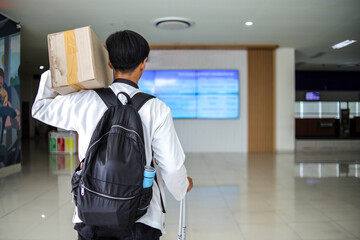 Back View of Muslim Man Carrying Cardboard Box at Terminal, Ready for Homecoming during Eid.
