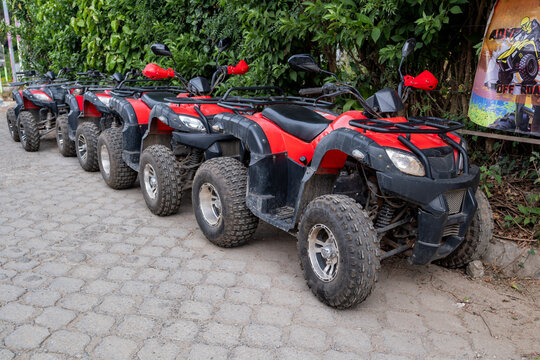 Row of a tour ATV quad bikes for rent parked on the street of a small tourist town.