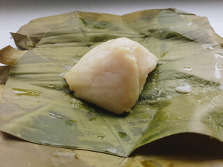 Nagasari is a traditional cake from Indonesia, made from rice flour, sago flour, coconut milk and sugar filled with bananas.  Nagasari or nogosari or banan cake isolated on white.  Selected focus.