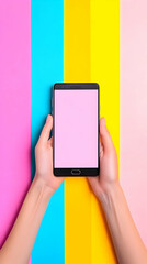 Hands hold smartphone with pink screen against vibrant colorful background, illustrating mobile app design concept.