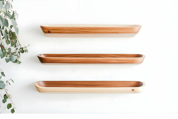 Three Wooden Boat-Shaped Shelves Adorn a White Wall, Creating a Minimalist and Elegant Display