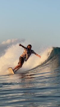 Vertical video of a long-haired male surfer surfing in the Indian Ocean.Wide angle shot.Slow motion video