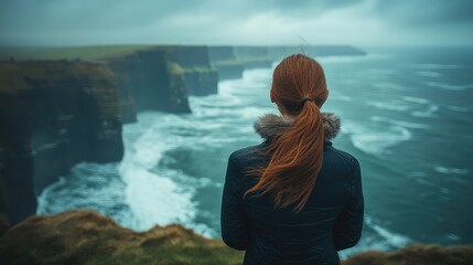 Fototapeta premium A woman gazing at the dramatic ocean view from the cliffs