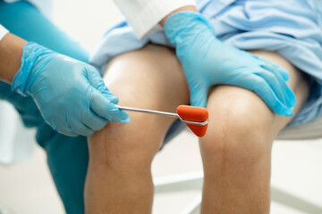 Asian doctor physiotherapist examining, massaging and treatment knee and leg of senior patient in...