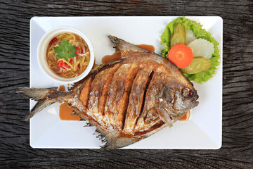 Deep Fried Pomfret with Fish Sauce isolated shot from above on a rustic texture 