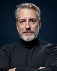 Obraz premium A mature man with a well-groomed beard poses confidently in a black turtleneck against a dark background, exuding charisma and sophistication.