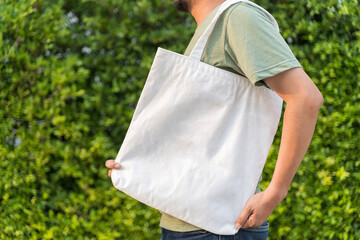 Man is holding bag canvas fabric for mockup blank template. Tote bag fabric cloth shopping sack