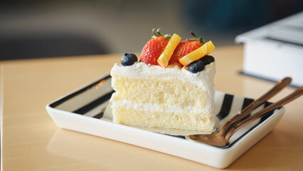 A delicious slice of cake topped with fresh fruit and cream, served on a striped plate, ideal for a...