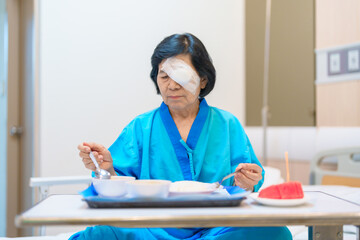 Senior Woman eating food after eye surgery in hospital . Eye disease, Cataract,  Glaucoma, Age...