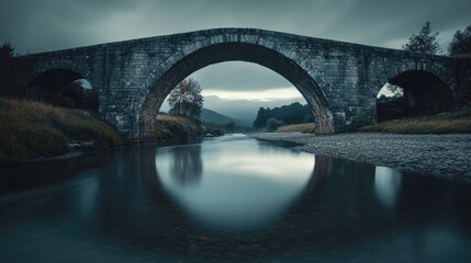A dramatic stone bridge spanning a river with mountainous scenery