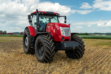 Red tractor working in a field on a bright sunny day. The concept of work in a fields and agriculture industry.