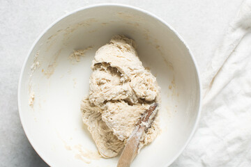 Overhead view of hot cross bun dough being mixed in a white mixing bowl, process of making hot cross buns