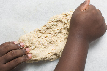 Overhead view of hot cross bun dough being kneaded in a white countertop, process of making hot...