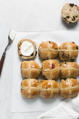 Overhead view of hot cross buns on white parchment paper, top view of hot cross buns on a white background, process of making hot cross buns