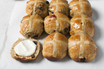 Overhead view of hot cross buns on white parchment paper, top view of hot cross buns on a white background, process of making hot cross buns