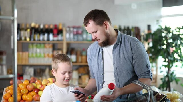 European man with son customer at shop scan QR code on milk bottle using phone camera. Client study composition, manufacturer information of product using application. Visitor examines product