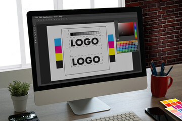 graphic designer using a tablet and computer to create a brand logo with a colour palette in...