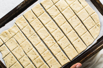 Overhead view of crackers dough on parchment paper being sliced, cutting cracker biscuit dough on...