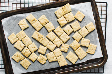 Overhead view of homemade crackers on parchment paper, top view of freshly baked cracker biscuits, process of making crackers
