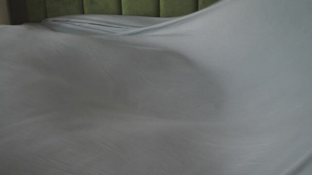 Making a bed with fresh linen in a cozy bedroom setting