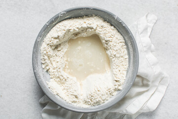 Overhead view of bagel dough being mixed in grey bowl, top view of homemade bagel dough being mixed in bowl, process of making bagels