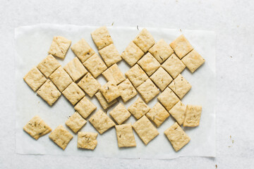 Overhead view of homemade crackers on parchment paper, top view of freshly baked cracker biscuits, process of making crackers
