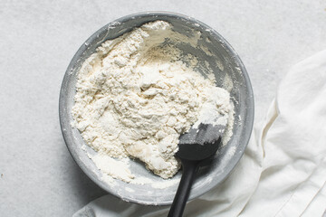 Overhead view of bagel dough being mixed in grey bowl, top view of homemade bagel dough being mixed in bowl, process of making bagels