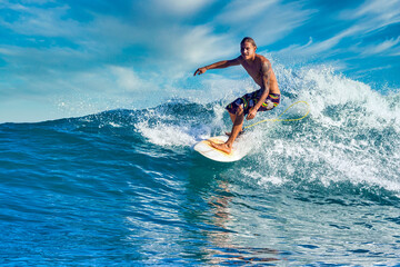 Male surfer on a blue wave at sunny day