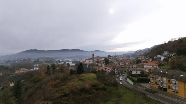 Scenic aerial view of a picturesque village surrounded by hills and mist.