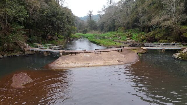 Aerial view of the Gruta India Natural Park, located in Misiones, Argentina, featuring the serene waterway and footbridge surrounded by lush greenery