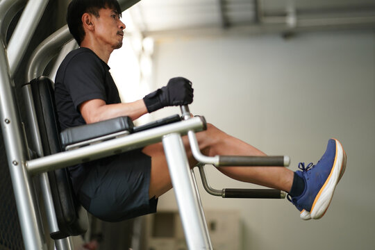 Asisn man doing abdominal exercises with machine in gym.
