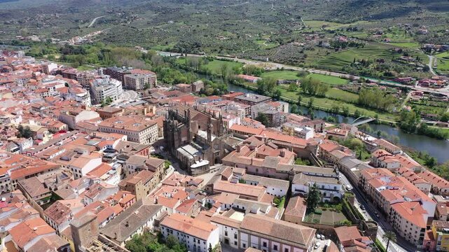 Picturesque aerial view of Plasencia city located in valley of Jerte river overlooking terracotta tiled roofs of residential buildings and medieval cathedral complex in spring, Extremadura, Spain