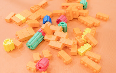 Obraz premium Colorful toy building blocks and balls scattered across a bright orange surface, creating a playful and abstract composition.