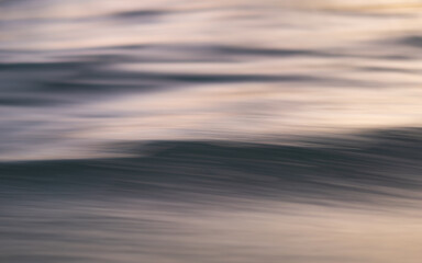 Abstract photograph of the ocean's surface taken from a moving boat. The motion blur creates a dreamy, ethereal effect, with the water's texture and subtle color variations highlighted.