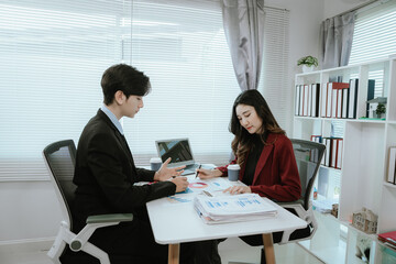 Team of corporate professionals working together in modern office to analyze financial charts and business reports. Businesswoman leading strategic discussion.