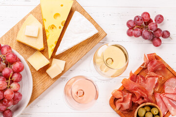 A delectable arrangement of various cheeses, fresh grapes, prosciutto and wine
