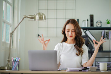 A woman is sitting at a desk with a laptop and a cup of coffee