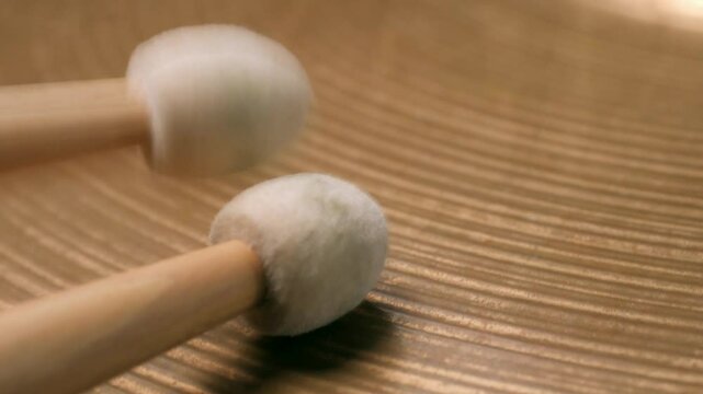 Macro footage. Drummer playing with felt tip percussion mallet sticks on plate hi hat. Slowmotion.